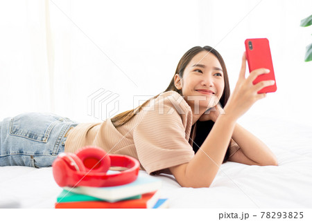 Happy young asian woman using video call with mobile phone to friends in bedroom Happy young asian woman using video call with mobile phone to friends in bedroom 78293825