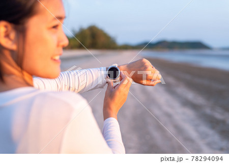 Sportswomen using smart watch for running and checking device at the beach during sunset Sportswomen using smart watch for running and checking device at the beach during sunset 78294094