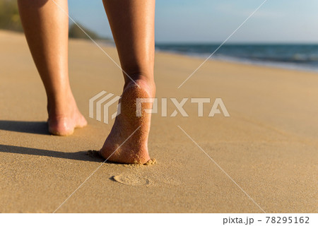 Close up of barefoot woman walking on the beach during sunset,Back view,Vacation and holiday concept Close up of barefoot woman walking on the beach during sunset,Back view,Vacation and holiday concept 78295162
