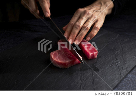 Female cook preparing a piece of bluefin tuna to make sushi. Asian food concept Female cook preparing a piece of bluefin tuna to make sushi. Asian food concept 78300701