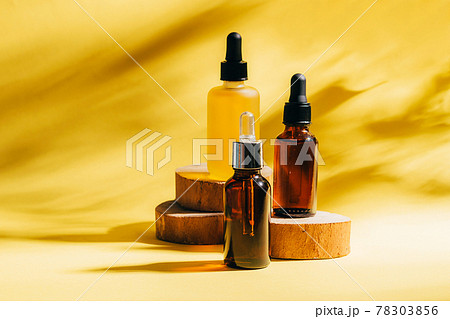 Cosmetics for face body for SPA procedures. Aromatherapy essential oil gel serum on wooden podiums yellow background 78303856