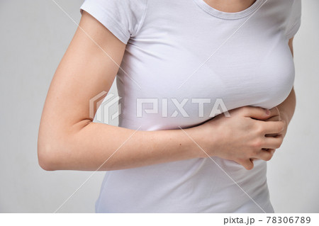 A girl in a white T-shirt is massaging under her breasts. The concept of intercostal neuralgia. A girl in a white T-shirt is massaging under her breasts. The concept of intercostal neuralgia. 78306789