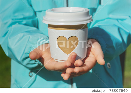 paper cup with carved white heart in children's arms of child in blue jacket paper cup with carved white heart in children's arms of child in blue jacket 78307640