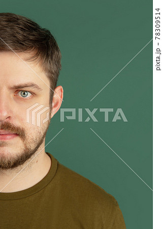 Cropped portrait of young Caucasian man isolated on dark green studio background. Concept of facial expressions Cropped portrait of young Caucasian man isolated on dark green studio background. Concept of facial expressions 78309514