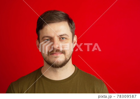 Portrait of young Caucasian man isolated on bright red studio background. Concept of facial expressions, human emotions. 78309587