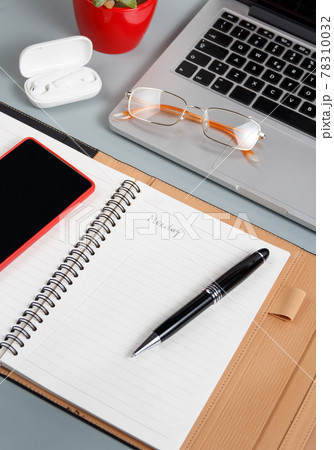 Laptop, cell phone and opened agenda on a grey desk close up. Laptop, cell phone and opened agenda on a grey desk close up. 78310032