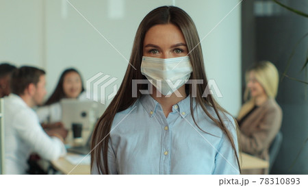 Portrait of young businesswoman in medical mask. Woman business, sales manager worker in large coworking open space. Healthcare at workspace. Portrait of young businesswoman in medical mask. Woman business, sales manager worker in large coworking open space. Healthcare at workspace. 78310893