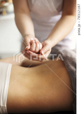 Crop masseuse using massage oil during skincare procedure 78312187