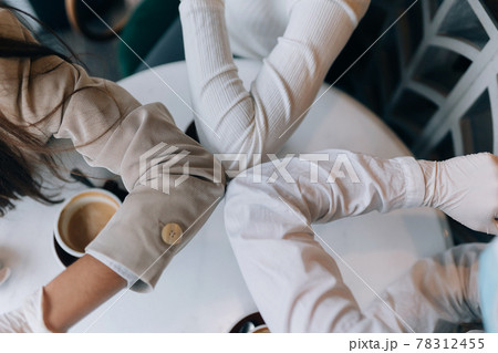 Co-workers in protective masks giving high five with elbows. Co-workers in protective masks giving high five with elbows. 78312455