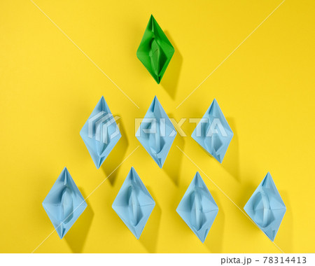 group of paper boats on a yellow background. concept of a strong leader in a team, manipulation of the masses, following new perspectives 78314413