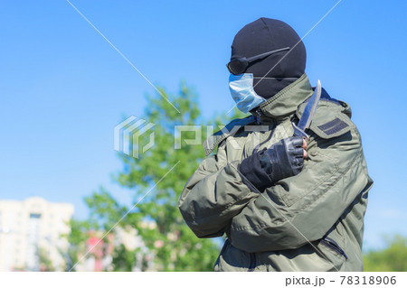 Modern dangerous and armed criminal in balaclava and medical mask among city streets Modern dangerous and armed criminal in balaclava and medical mask among city streets 78318906