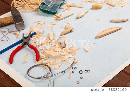 Handmade wooden fishing tacles graph paper background with tools and blanks. Handmade wooden fishing tacles graph paper background with tools and blanks. 78322169