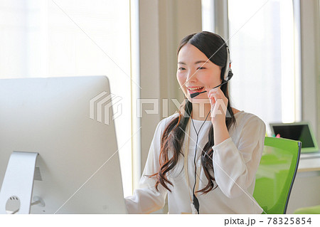 ヘッドセットに手を添え笑顔で話すオペレーター 78325854