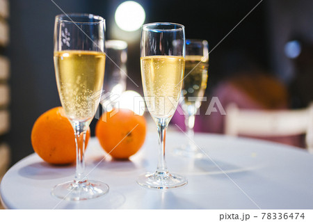 Glasses of white champagne and oranges on white table Glasses of white champagne and oranges on white table 78336474