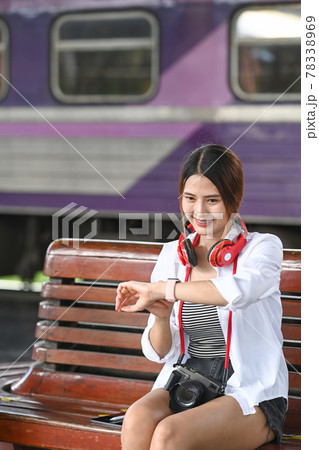 Young female traveller checking time on her smartwatch and waiting train at station. 78338969