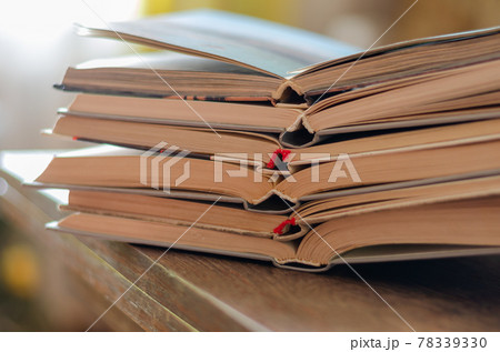 A stack of open textbooks on a desk. 78339330