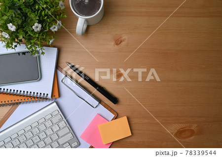High angle view of simple workspace with smart phone, notebook, sticky note and coffee cup on wooden desk. 78339544