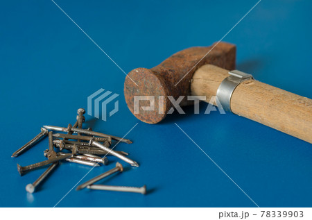Old hammer and a set of nails on a blue background. Old hammer and a set of nails on a blue background. 78339903