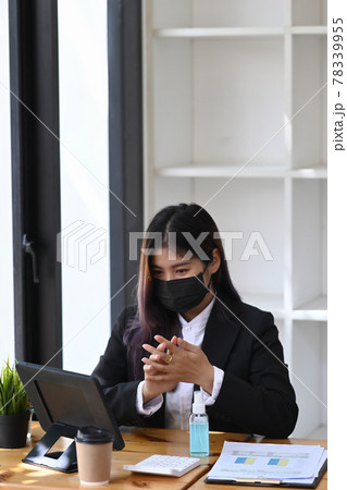 Businesswoman in protective mask using hand sanitizer gel at her office. Businesswoman in protective mask using hand sanitizer gel at her office. 78339955