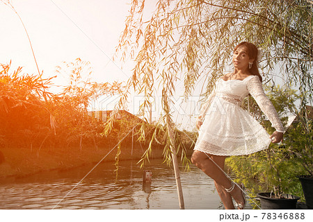 Pretty Asian woman posing relax under the tree on the canal in the park. 78346888