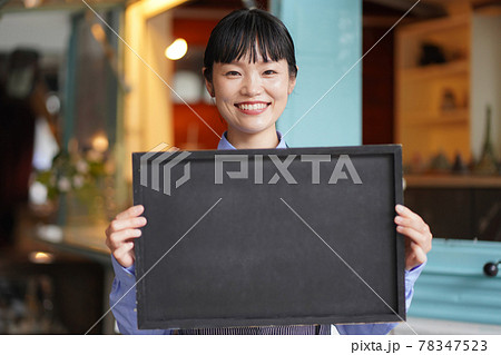 キッチンカーの前でメッセージボードを持つ女性店員 78347523