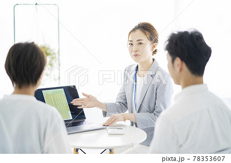 夫婦に説明するスーツ姿の女性 78353607