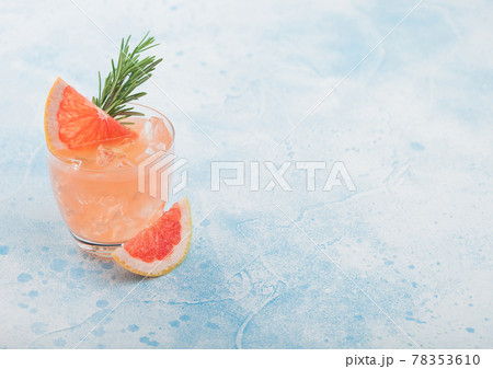 Cold summer grapefruit cocktail in glass with ice cubes and rosemary with grapefruits slice on blue background 78353610