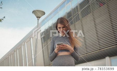 Portrait woman looking at smartphone while running outdoor. Close-up Of A Young Beautiful Sports Fitness Girl Holding A Smartphone In The Hands, Using A Fitness App. Modern City Shooting On the Street Portrait woman looking at smartphone while running outdoor. Close-up Of A Young Beautiful Sports Fitness Girl Holding A Smartphone In The Hands, Using A Fitness App. Modern City Shooting On the Street 78353699
