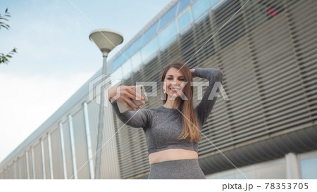 POV of the charming and happy girl. Close-up Of A Beautiful Sports Girl Holding A Smartphone. Close up of the young caucasian woman having a video chat on the modern building background. Outdoors. one 78353705