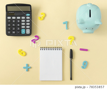 Top view of a table with a calculator, notepad, piggy bank and numbers. The concept of calculations, planning. 78353857