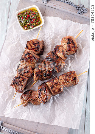 Grilled sirloin tips or beef meat skewers with chimichurri sauce, on wooden tray, vertical, top view 78354515