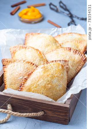 Homemade small peach and cinnamon hand pies with crust dough, sprinkled with sugar, on wooden tray, vertical Homemade small peach and cinnamon hand pies with crust dough, sprinkled with sugar, on wooden tray, vertical 78354531