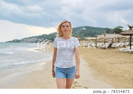 Happy beautiful young woman walking on beach Happy beautiful young woman walking on beach 78354875