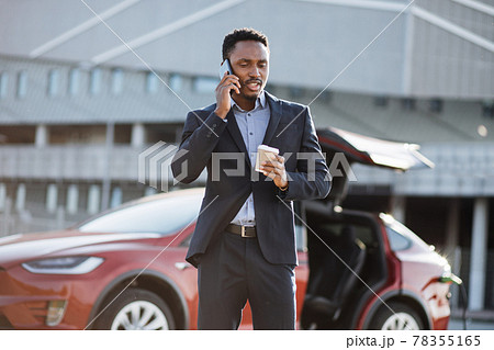 Man having mobile talk while waiting for electric car Man having mobile talk while waiting for electric car 78355165