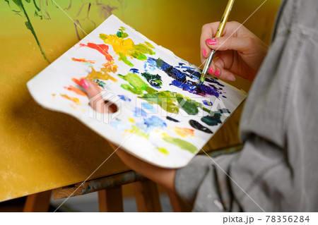 Female Artist mixes paints on the palette, painter at the studio, creator makes piece of art. 78356284