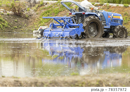 水を張った田んぼ。トラクターで作業する様子 78357972
