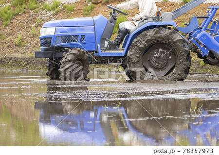 水を張った田んぼ。トラクターで作業する様子 78357973