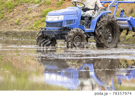 水を張った田んぼ。トラクターで作業する様子 78357974