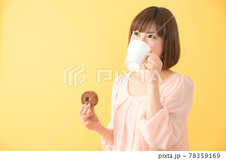 おやつを片手にコーヒーを飲む若い女性 おやつを片手にコーヒーを飲む若い女性 78359169