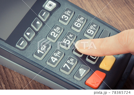 Hand of woman entering PIN code on payment terminal. Cashless paying for shopping. Finance concept 78365724