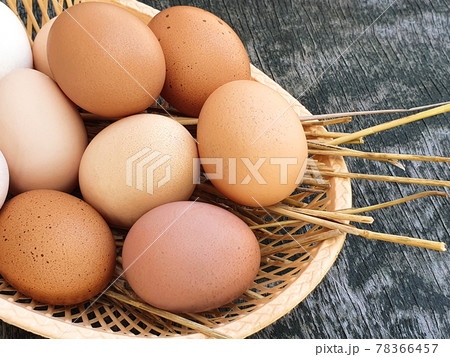 Domestic hens eggs in basket on old wooden texture background. Natural white and red brown eggs. Closeup, top view. 78366457