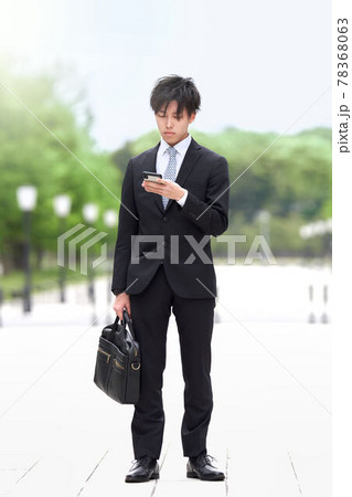 立ったままスマホを見る若いビジネスマン 立ったままスマホを見る若いビジネスマン 78368063