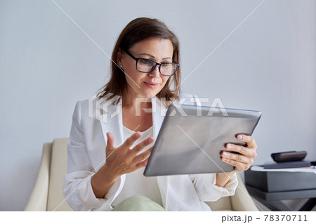 Talking businesswoman looking at screen of digital tablet 78370711