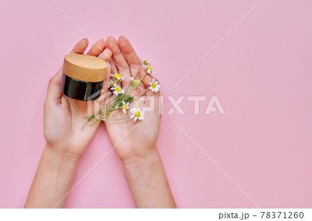 Woman hands, flowers and glass bottle with cosmetic product on pink background 78371260