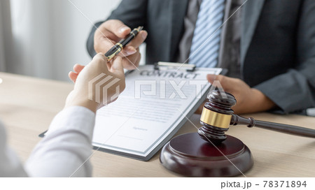 Attorney or lawyer handing client a pen to sign a business contract, Signing the contract according to the terms and conditions, scales of justice, law hammer, Concept of litigation and legal services 78371894
