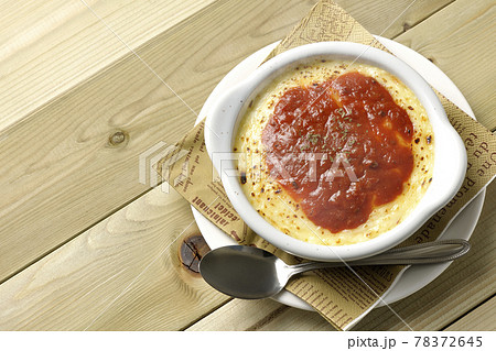 ペーパーナプキンと溶けて焦げ目がついたたっぷりチーズのドリア、グラタンとシルバースプーンを俯瞰で撮影 78372645