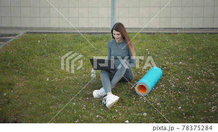Happy woman, sitting laptop outdoor. Smiling fit girl typing on laptop computer at city background. Person working on laptop outside. Attractive girl, corporate startup office employee working outdoor 78375284