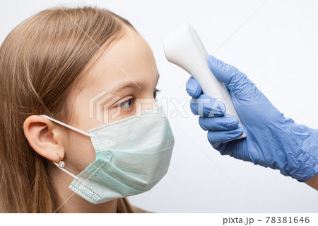 Doctor using infrared thermometer checking body temperature of girl wearing surgical mask - epidemic virus outbreak concept Doctor using infrared thermometer checking body temperature of girl wearing surgical mask - epidemic virus outbreak concept 78381646
