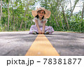little girl sitting on the middle of asphalt road 78381877