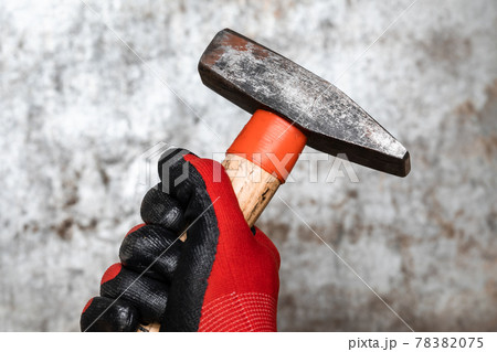 Mechanic holding hammer against metal background Mechanic holding hammer against metal background 78382075